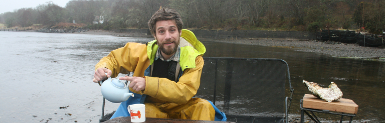 Angus Vajk from the Caledonian Oyster Co. Ltd. on a seat made from recycled oyster trestle tables and reclaimed boat wood, beside Loch Creran.